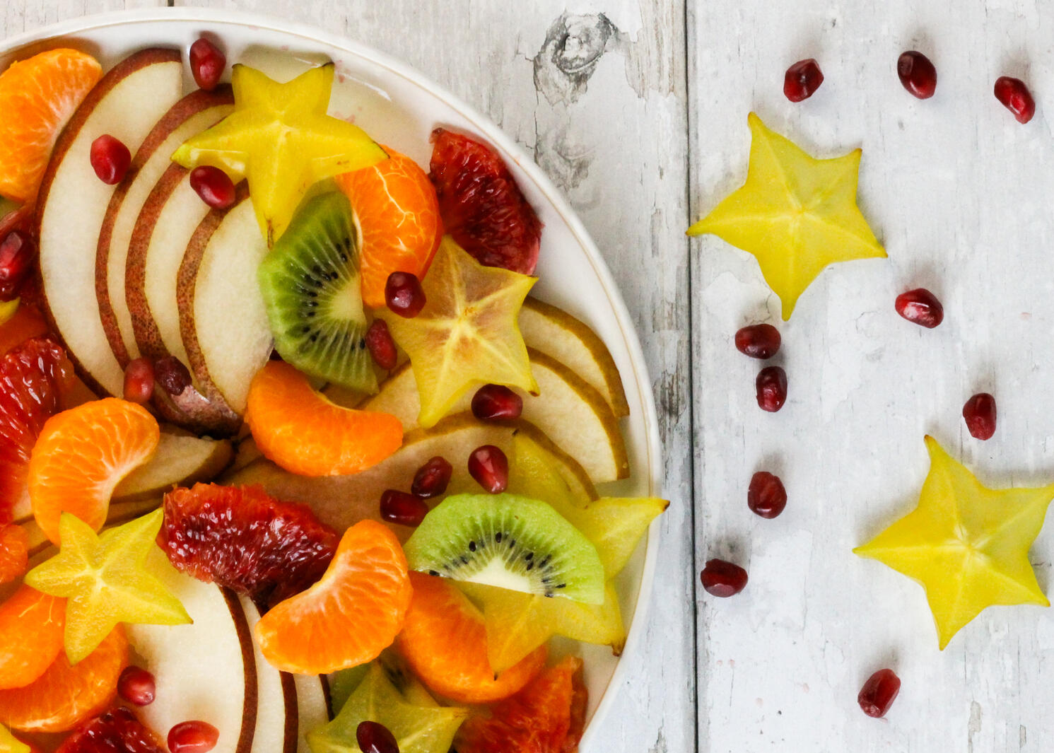A fruit salad with starfruit and pomegranate.